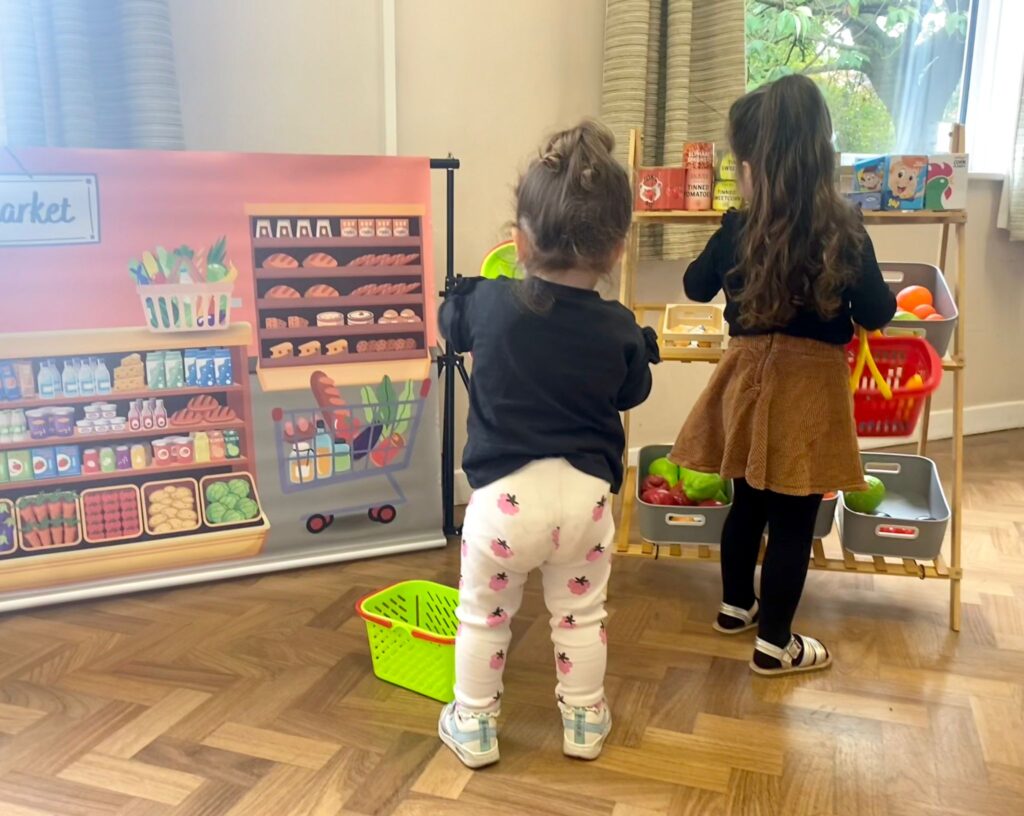 Children taking part in imaginative role play at a supermarket-themed play area