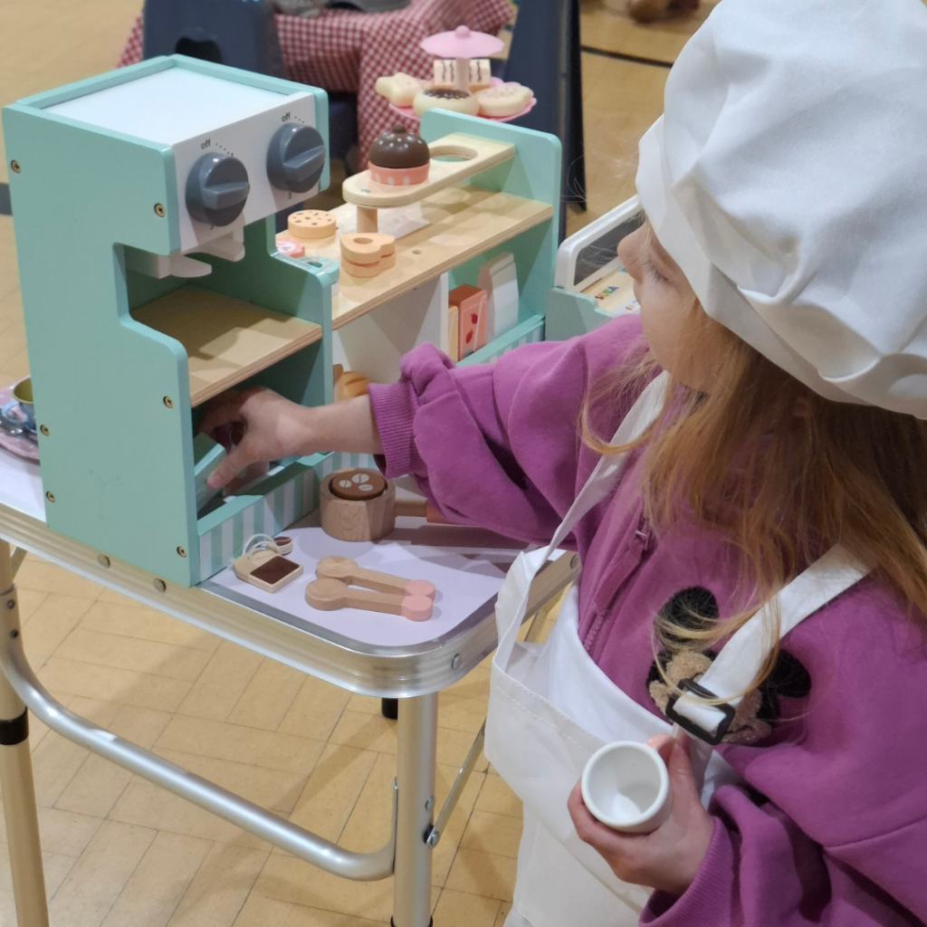 Child playing café role play with toy kitchen in a play-based learning activity