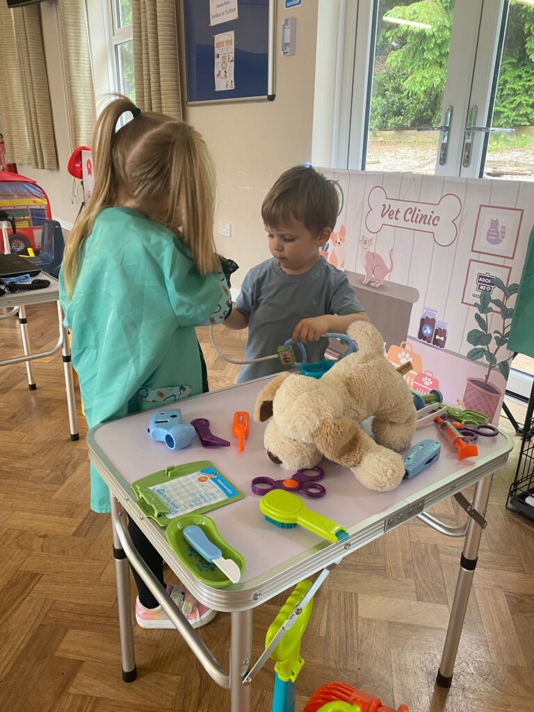 Two young children engaging in imaginative play at The Little Village of Imagination, pretending to be vets caring for a toy dog in a pretend Vet Clinic role play setup