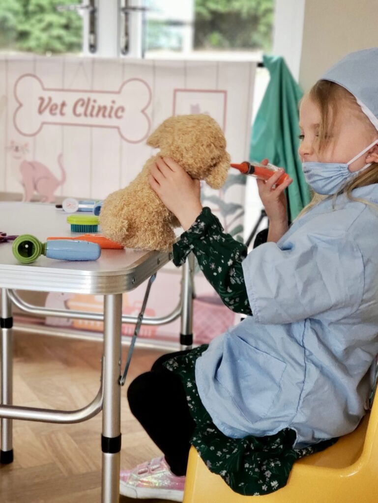 Child enjoying vet role play activity, using toy medical kit to care for a teddy dog in a pretend veterinary clinic