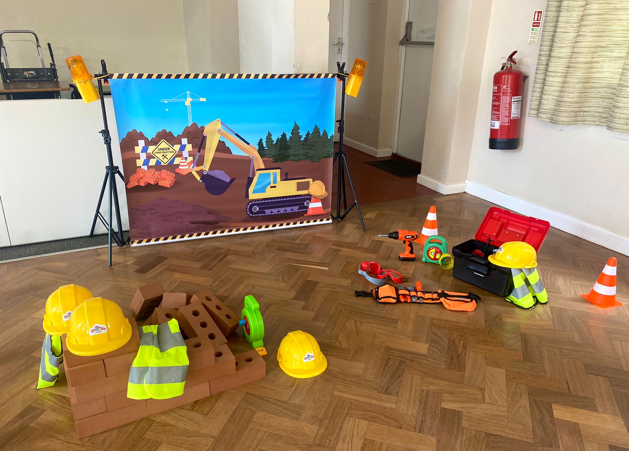Construction site role play area set up for a children's party in Walsall, with hard hats, hi-vis vests, foam bricks, cones and toy tools
